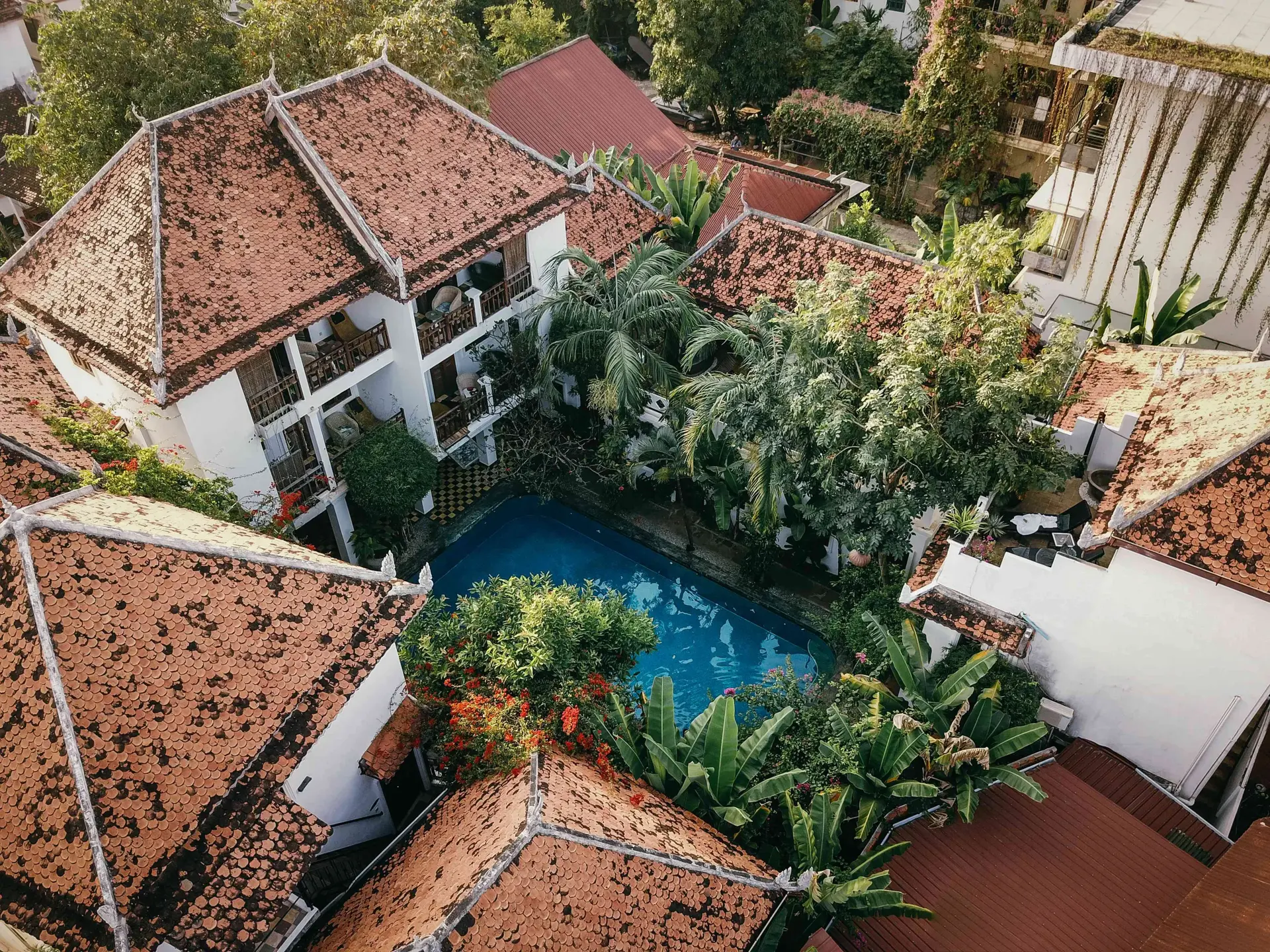 Aerial view over the terracotta-tiled roofs and courtyard swimming pool in Siem Reap